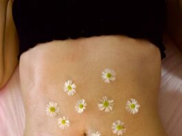 Woman's belly adorned with calming chamomile flowers for relaxation therapy.