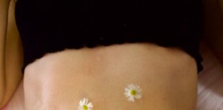Woman's belly adorned with calming chamomile flowers for relaxation therapy.