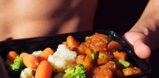 person holding black plastic container with food